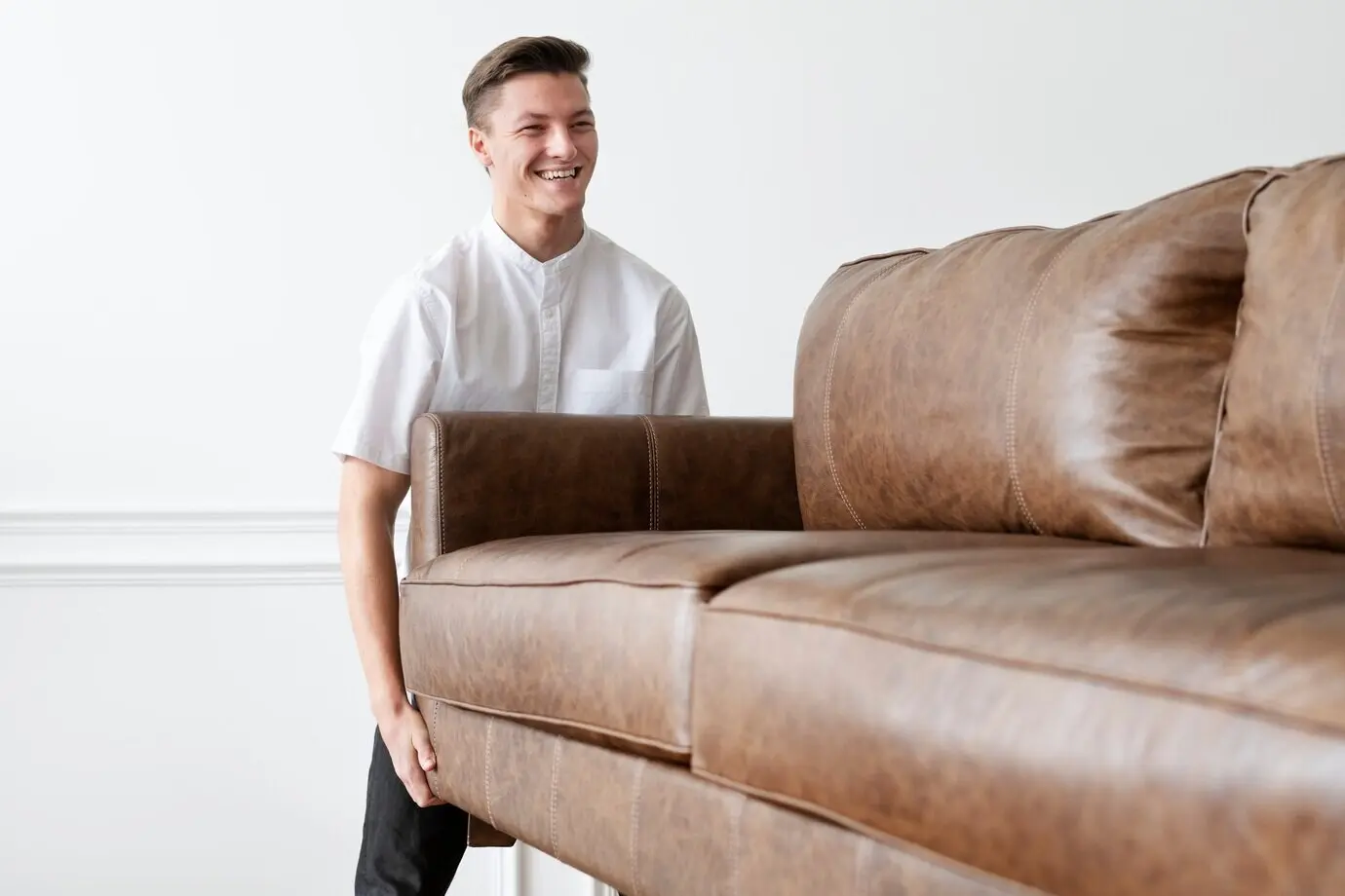 Ein Mann bewegt ein Sofa in einem neuen Zuhause.